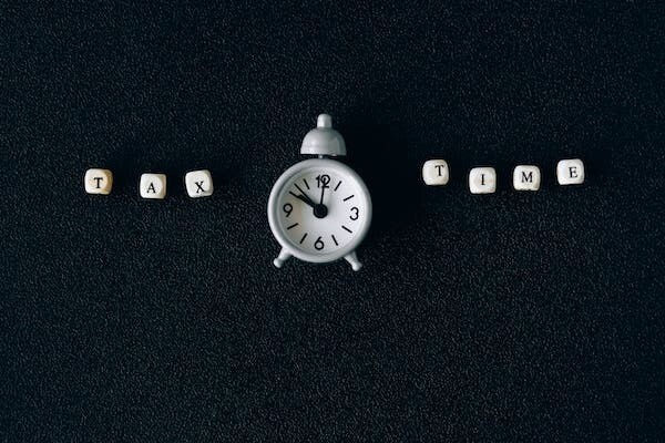 image of a clock and tax time spelled out in Scrabble letters